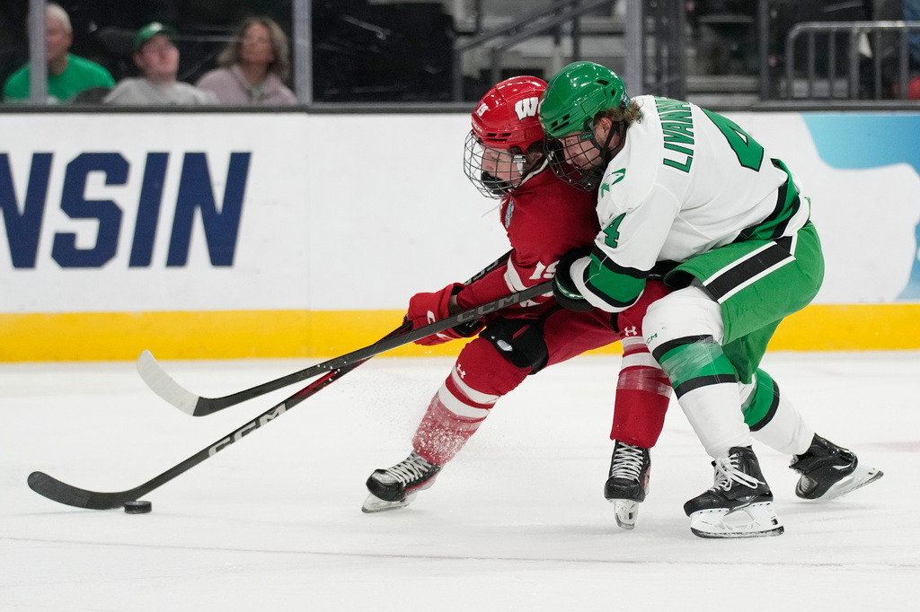 Wisconsin defenseman Joe Palodichuk (14) skates against North Dakota defenseman Jake Livanavage (4) in the second period of a semifinal game of the NCAA Frozen Four men's college hockey tournament Thursday, April 9, 2026, in Las Vegas. (AP Photo/John Locher)