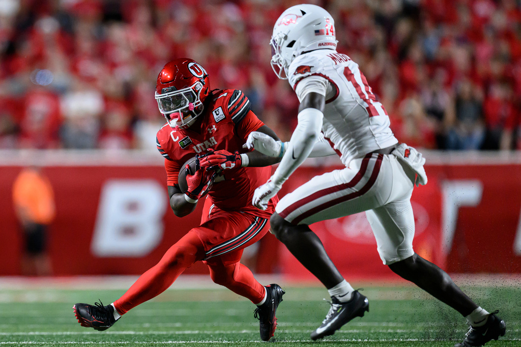 Utah running back Wayshawn Parker, left, runs the ball as Arkansas defensive back Kyeaure Magloire, right, looks to make the tackle during the second half of an NCAA college football game Saturday, Sept. 12, 2026, in Salt Lake City. (AP Photo/Tyler Tate)