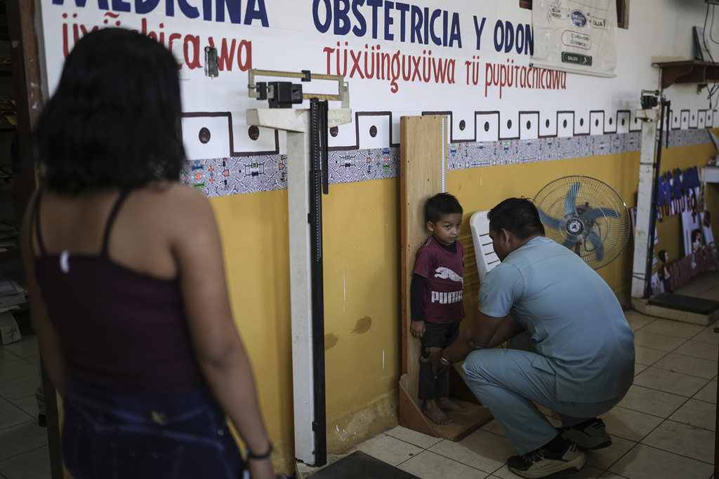 A doctor measures a child's height at the health center in Santa Rosa, Peru, an island on the Amazon River at the triple border with Colombia and Brazil, Monday, Aug. 18, 2025.(AP Photo/Ivan Valencia)