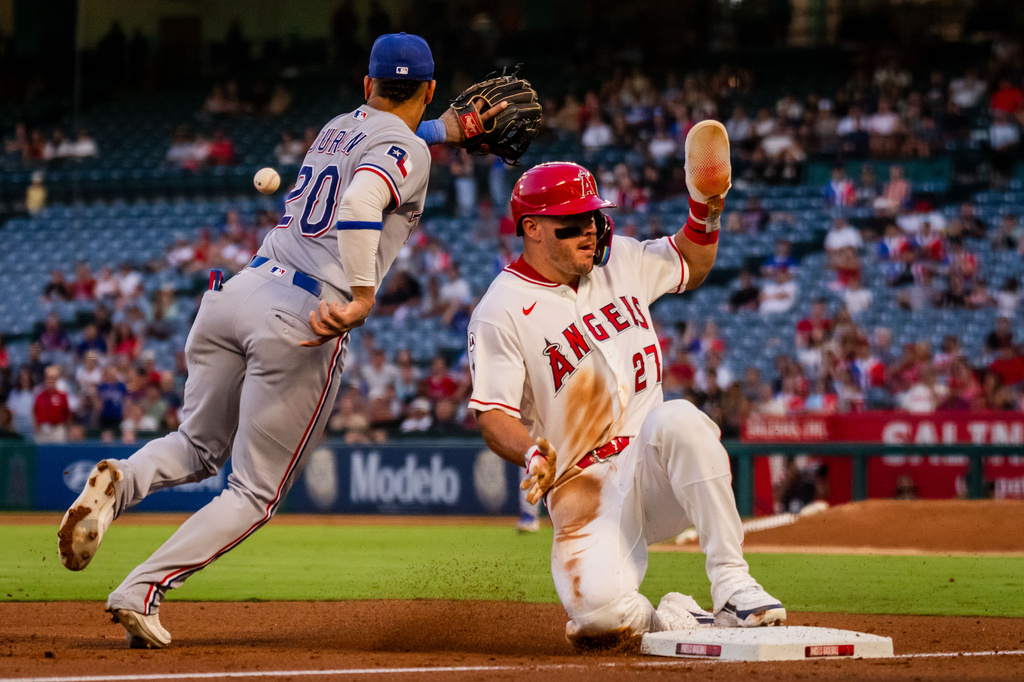 Los Angeles Angels center fielder Mike Trout (27) beats the tag at 3rd base against Texas Rangers shortstop Ezequiel Duran (20) during the 3rd inning of a baseball game, Tuesday, Aug. 11, 2026, in Anaheim, Calif. (AP Photo/Ethan Swope)