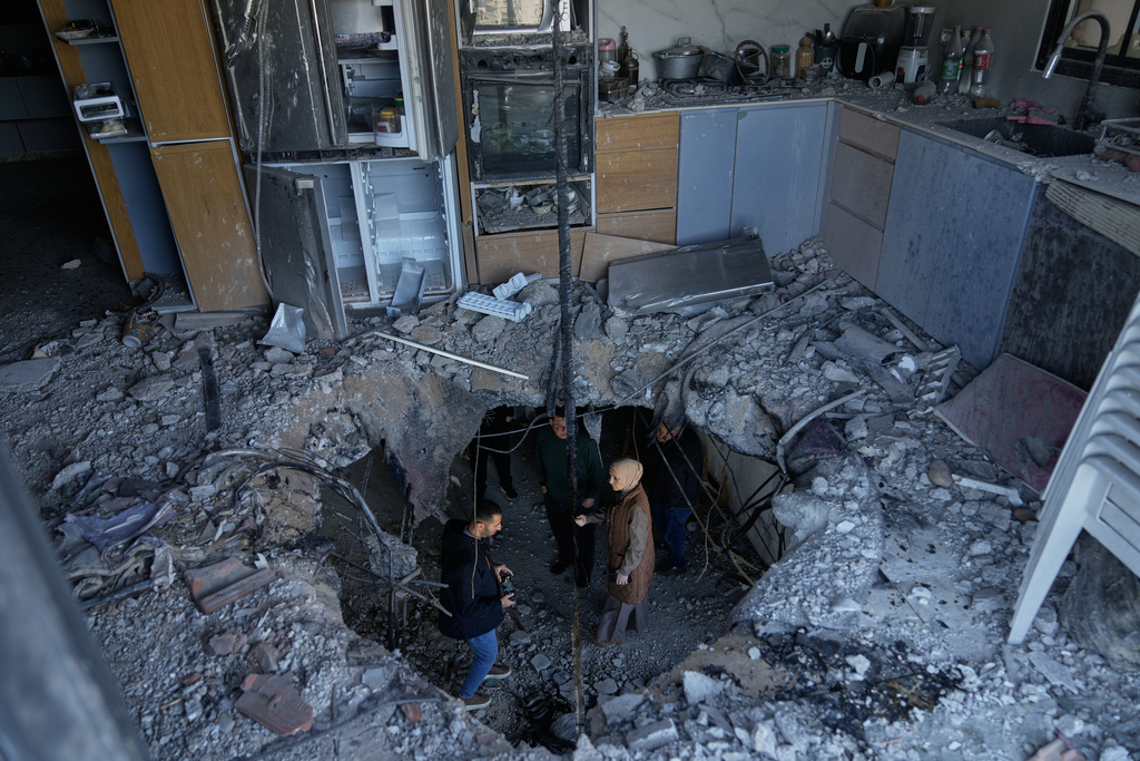 Residents inspect damage which according to them was caused by fragments of an intercepted Iranian rocket that landed on a Palestinian three story building, in West Bank town of Biddya, west of Salfit, Wednesday, March 11, 2026. (AP Photo/Majdi Mohammed)
