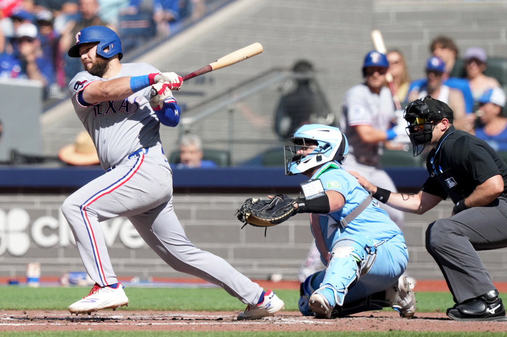Texas Rangers first baseman Jake Burger (21) hits a single during fifth inning of a baseball game against the Toronto Blue Jays, in Toronto, Saturday, June 27, 2026. (Nathan Denette/The Canadian Press via AP)