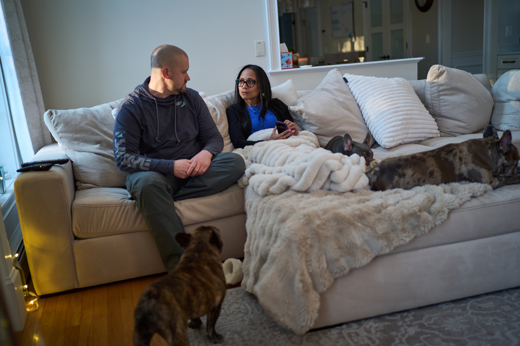 Ruth Wilson, right, whose lupus took six years to diagnose, sits with her husband, Jim, and their three dogs at their home, Sunday, Jan. 12, 2025, in Littleton, Mass. (AP Photo/David Goldman)
