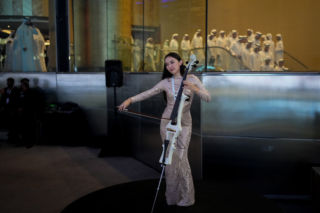 A performer plays a violin as Emirati officials are seen behind during the Dubai World Cup at Meydan Racecourse in Dubai, United Arab Emirates, Saturday, March 28, 2026. (AP Photo/Altaf Qadri)