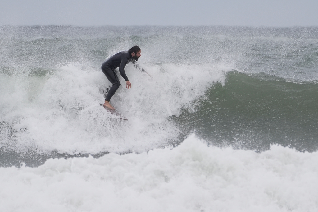 A surfer rides a wave during a nor'easter storm, Friday, Sept. 25, 2026, in Gloucester, Mass.(AP Photo/Robert F. Bukaty)