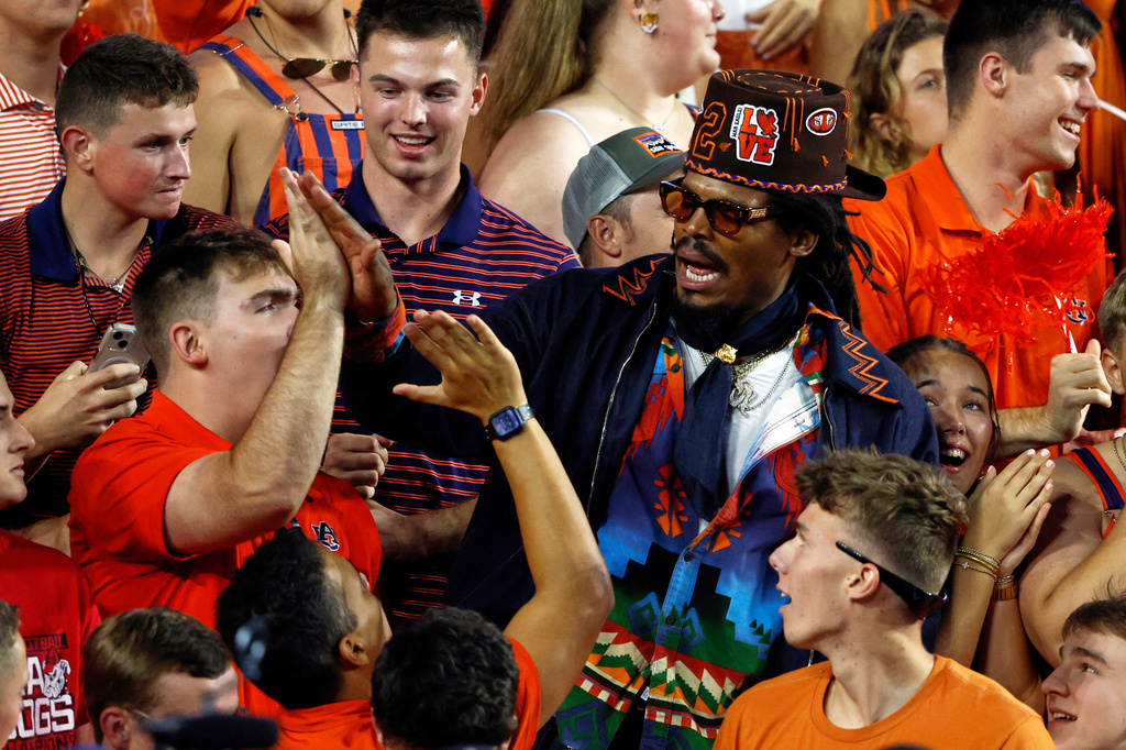 Former Auburn quarterback and NFL player Cam Newton celebrates with fans after a play during the first half of an NCAA college football game against Georgia, Saturday, Oct. 11, 2025, in Auburn, Ala. (AP Photo/Butch Dill)