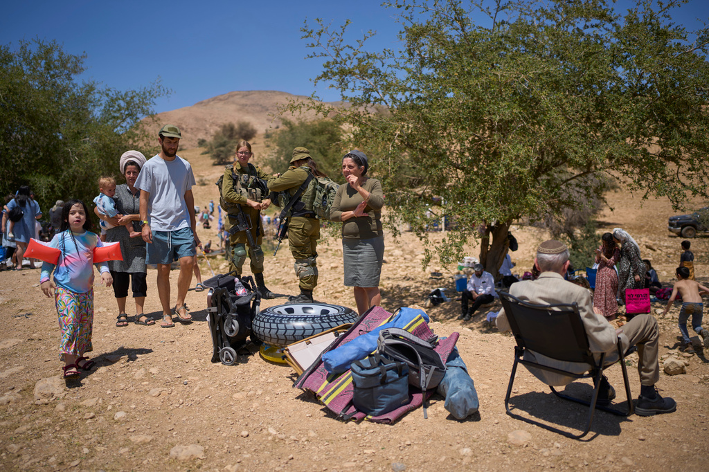 Soldiers stand guard while Israelis enjoy a day at a spring in Auja, in the Jordan Valley, during Israel's Independence Day on Wednesday, April 22, 2026, in the occupied West Bank. (AP Photo/Ohad Zwigenberg)