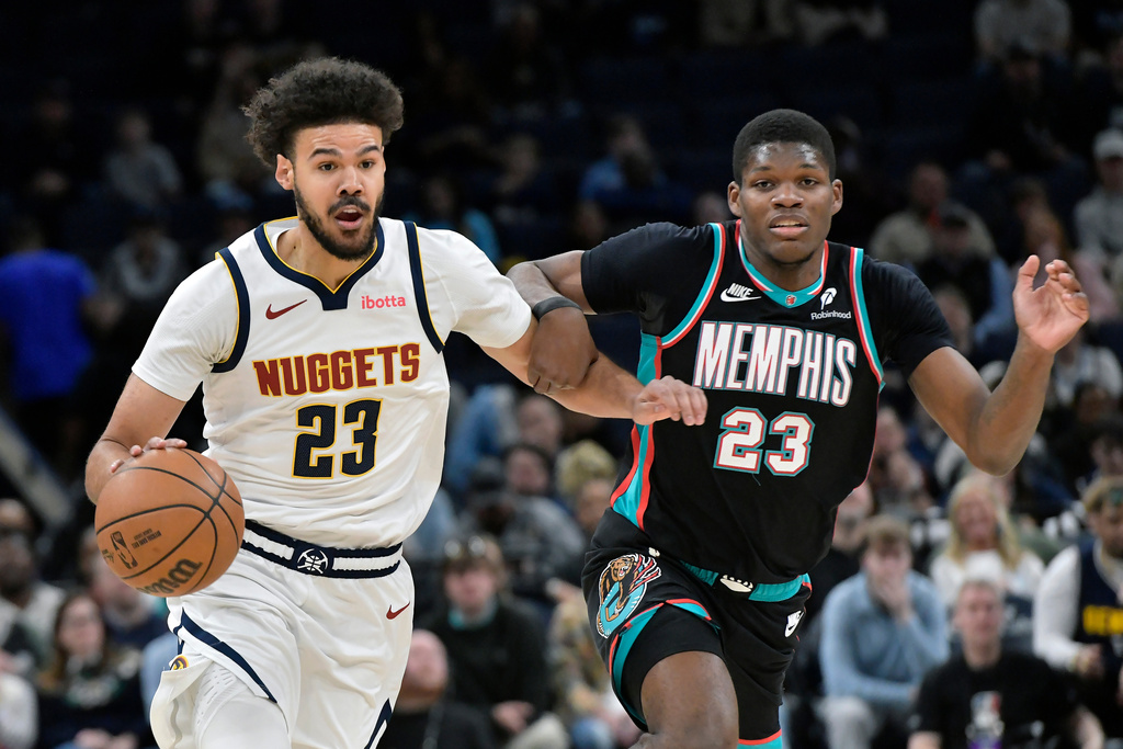 Denver Nuggets forward Cameron Johnson, left, handles the ball against Memphis Grizzlies forward Cedric Coward in the first half of an NBA basketball game Wednesday, March 18, 2026, in Memphis, Tenn. (AP Photo/Brandon Dill)