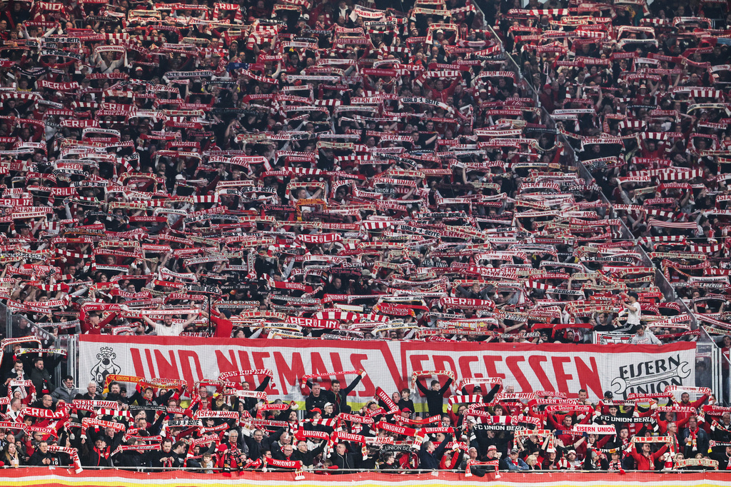 Union Berlin supporters hold up scarves and cheer during a Bundesliga soccer match between RB Leipzig and 1. FC Union Berlin, Friday, April 24, 2026, in Leipzig, Germany. (Jan Woitas/dpa via AP)