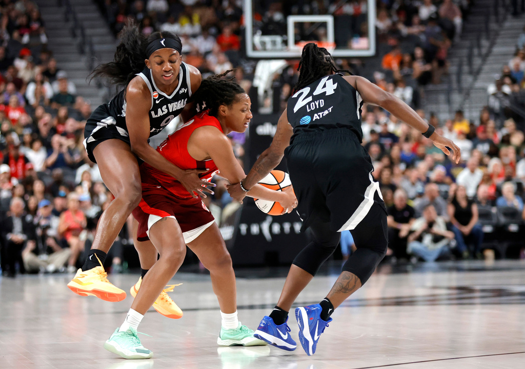 Indiana Fever guard Kelsey Mitchell, center, is fouled by Las Vegas Aces guard Jackie Young, left, as guard Jewell Loyd (24) looks on during the first half of an WNBA basketball game Sunday, July 5, 2026, in Las Vegas. (Steve Marcus/Las Vegas Sun via AP)