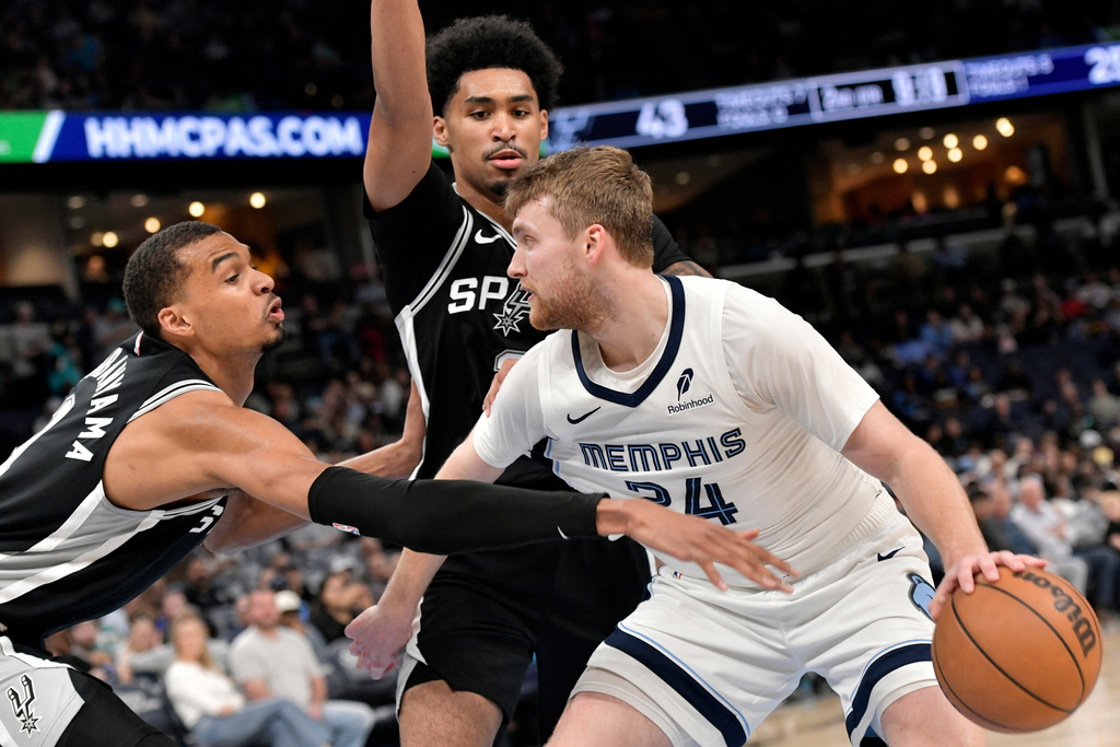 Memphis Grizzlies guard Cam Spencer (24) handles the ball against San Antonio Spurs forward Victor Wembanyama, left, and guard Dylan Harper, center, in the first half of an NBA basketball game Wednesday, March 25, 2026, in Memphis, Tenn. (AP Photo/Brandon Dill)