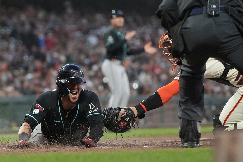 Arizona Diamondbacks' Ildemaro Vargas, left, slides home to score past San Francisco Giants catcher Andrew Knizner during the third inning of the second baseball game of a doubleheader, Saturday, Aug. 29, 2026, in San Francisco. (AP Photo/Jeff Chiu)