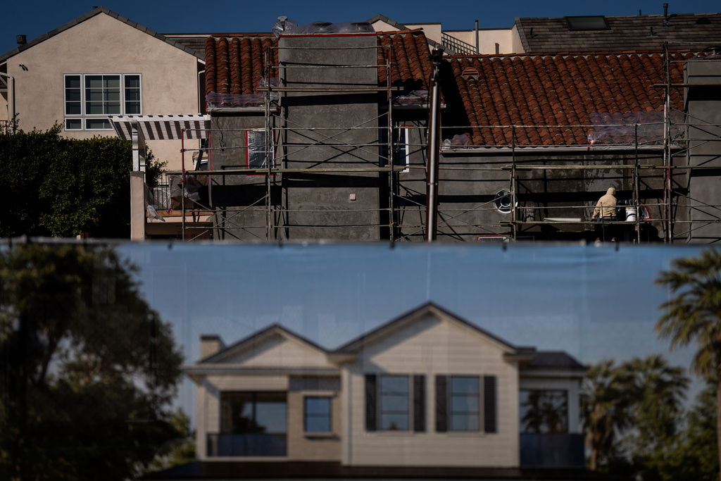 A rendering hangs on a fence in front of a home under construction in the Pacific Palisades neighborhood of Los Angeles, Friday, Dec. 5, 2025, months after the Palisades Fire. (AP Photo/Jae C. Hong)