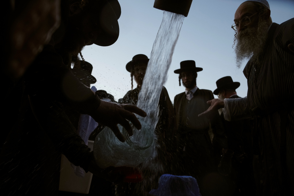 Ultra-Orthodox Jewish men gather at a mountain spring on the outskirts of Jerusalem to collect water for baking matzoh in preparation for the upcoming Passover holiday, Tuesday, March 31, 2026. (AP Photo/Mahmoud Illean)