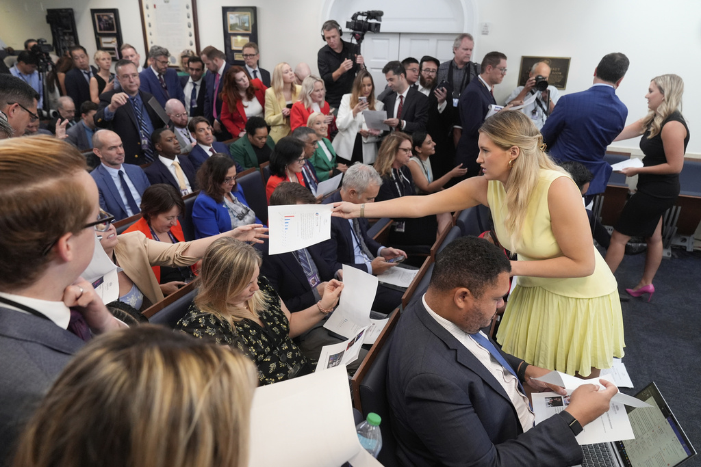 White House staff hand out documents before President Donald Trump arrives to speak with reporters in the James Brady Press Briefing Room at the White House, Monday, Aug. 11, 2025, in Washington. (AP Photo/Mark Schiefelbein)