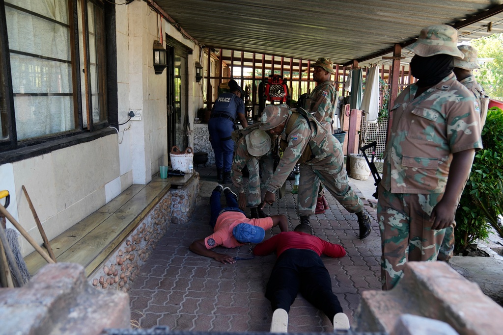 South African National Defense Force officers search suspects, in the Westbury township of Johannesburg, South Africa, Wednesday, March 11, 2026. (AP Photo/Themba Hadebe)