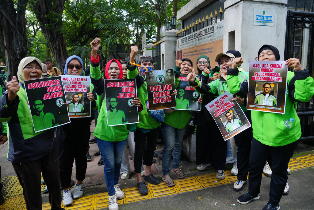 Ride hailing drivers hold posters supporting Nadiem Anwar Makarim, the co-founder of Indonesia's payments platform and ride hailing company Gojek and former education minister, as they shout slogans outside the Corruption Court where Makarim's trial hearing is held in Jakarta, Indonesia, Monday, Jan. 5, 2026. (AP Photo/Tatan Syuflana)