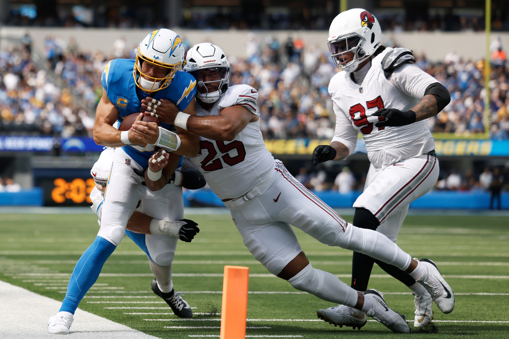 Los Angeles Chargers quarterback Justin Herbert, left, is hit by Arizona Cardinals linebacker Jack Gibbens, left rear, and linebacker Zaven Collins (25) as defensive tackle Walter Nolen III (97) follows the play during the first half of an NFL football game, Sunday, Sept. 13, 2026, in Inglewood, Calif. (AP Photo/Caroline Brehman)