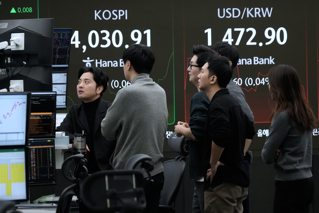 Currency traders watch monitors near a screen showing the Korea Composite Stock Price Index (KOSPI) and the foreign exchange rate between U.S. dollar and South Korean won, top right, at the foreign exchange dealing room of the Hana Bank headquarters, in Seoul, South Korea, Friday, Dec. 5, 2025. (AP Photo/Ahn Young-joon)