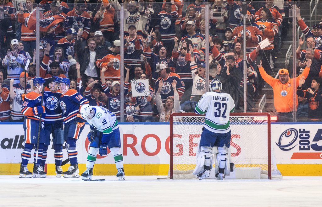 Edmonton Oilers' Josh Samanski (81), Colton Dach, second from left, and Trent Frederic (10) celebrate after a goal as Vancouver Canucks' Kirill Kudryavtsev (59) and goalie Kevin Lankinen (32) look on during first-period NHL hockey game action in Edmonton, Alberta, Thursday April 16, 2026. (Jason Franson/The Canadian Press via AP)