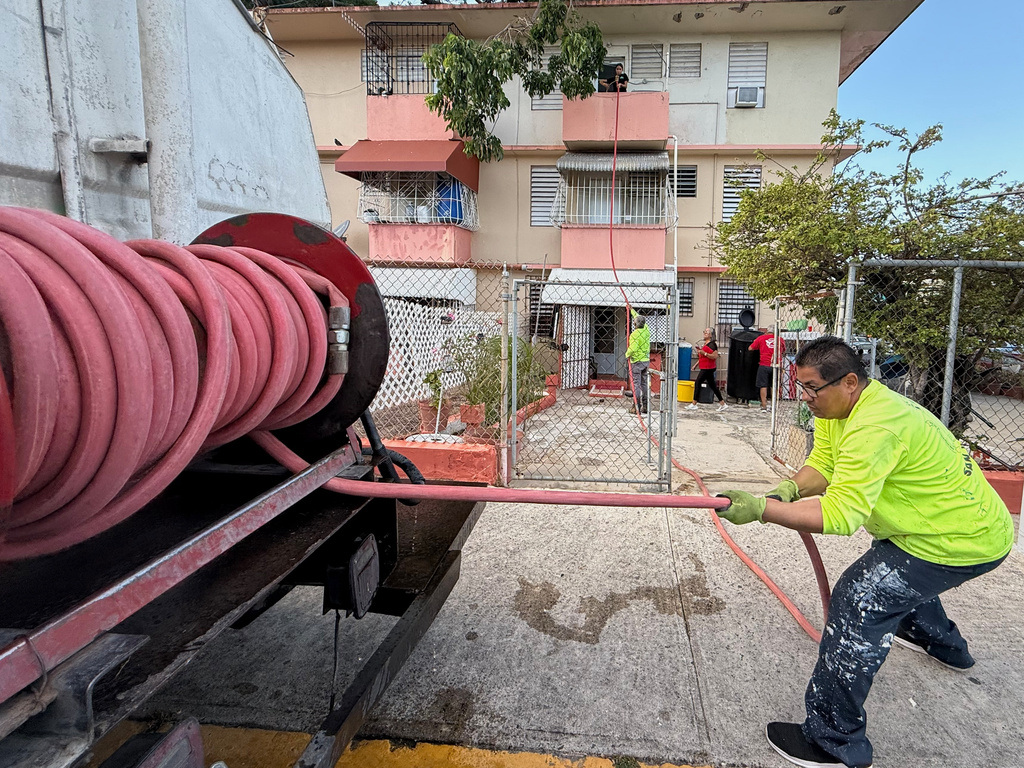Juan Lugo, a driver with San Juan's special projects department, delivers free, non-potable water to residents in the Villa Kennedy public housing complex in San Juan, Puerto Rico, Wednesday, June 10, 2026. (AP Photo/Danica Coto)