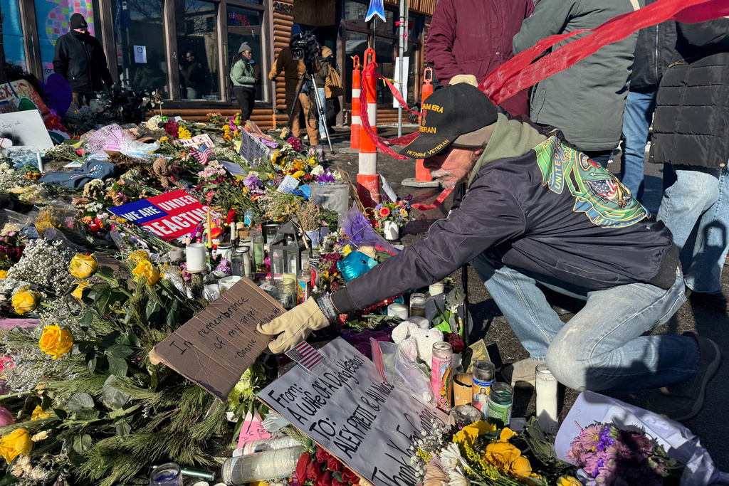 Vietnam war veteran Donnie McMillan places a sign that says "In remembrance of my angel" at a memorial set up at the location where Veterans Affairs nurse Alex Pretti was shot by U.S. federal agents, in Minneapolis, Wednesday, Jan. 28, 2026. (AP Photo/Jack Brook)