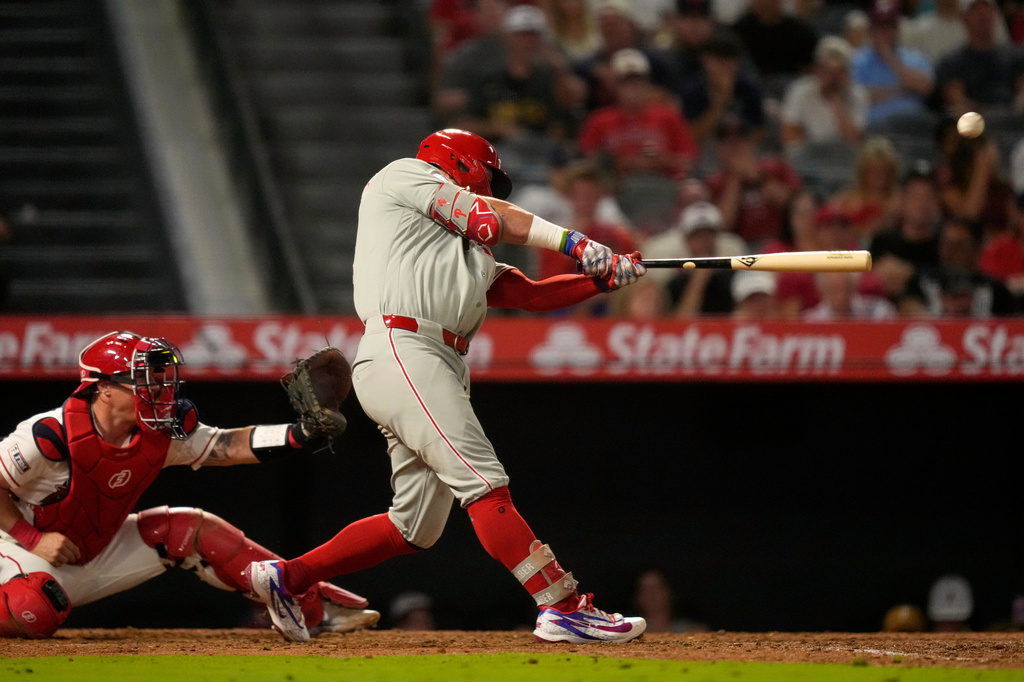 Philadelphia Phillies' Kyle Schwarber, right, hits an RBI double as Los Angeles Angels catcher Tyler Heineman watches during the 10th inning of a baseball game Saturday, Aug. 29, 2026, in Anaheim, Calif. (AP Photo/Mark J. Terrill)