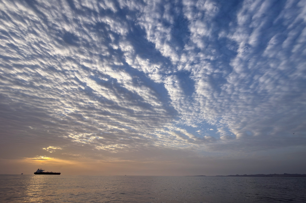The sun rises behind a tanker anchored in the Strait of Hormuz off the coast of Qeshm Island, Iran, Saturday, April 18, 2026. (AP Photo/Asghar Besharati)