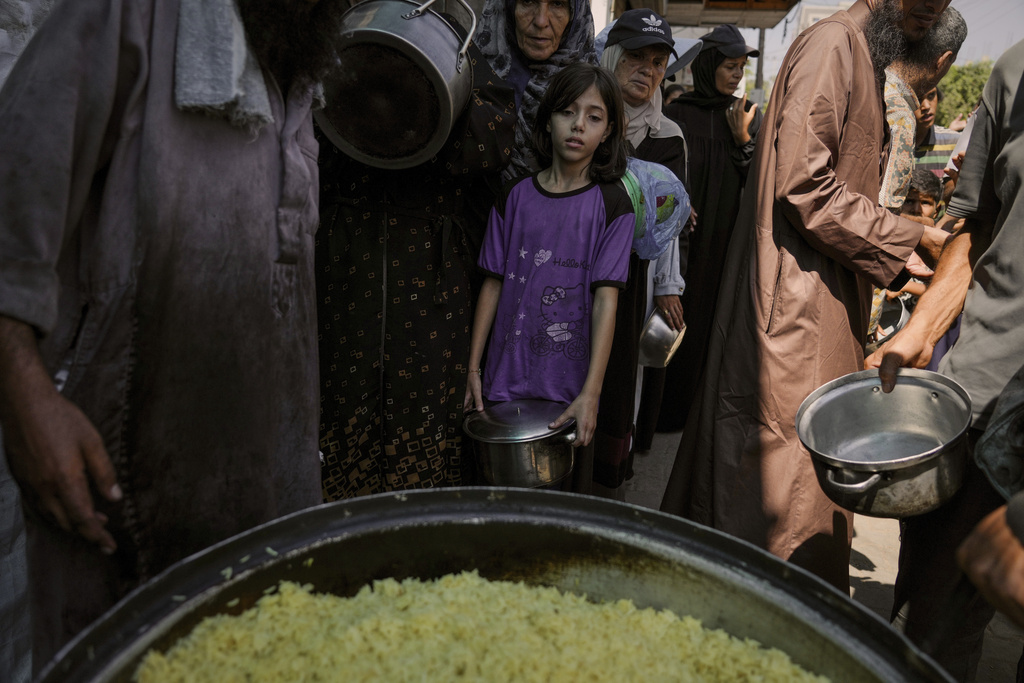 Palestinians line up to receive donated food at a community kitchen in Deir al-Balah, southern Gaza Strip, Saturday, Sept. 6, 2025. (AP Photo/Jehad Alshrafi)