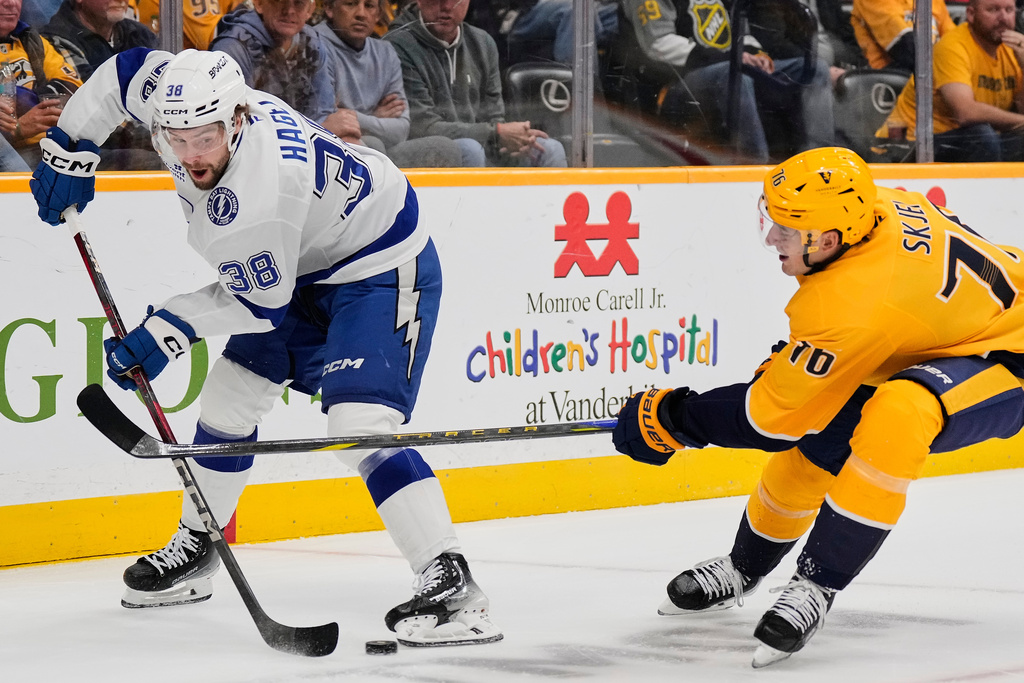 Tampa Bay Lightning left wing Brandon Hagel (38) passes the puck around Nashville Predators defenseman Brady Skjei (76) during the first period of an NHL hockey game Tuesday, Oct. 28, 2025, in Nashville, Tenn. (AP Photo/George Walker IV)