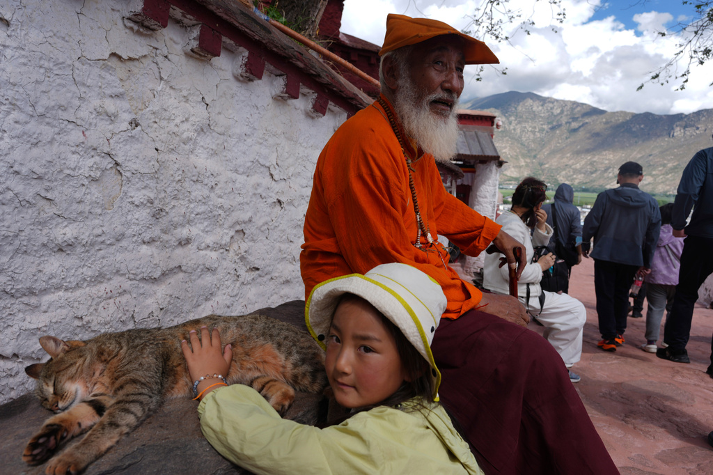 A child pets a cat during a visit to the Potala Palace in Lhasa in western China's Tibet Autonomous Region on Tuesday, July 21, 2026, as seen during a government organized visit for foreign journalists. (AP Photo/Ng Han Guan)