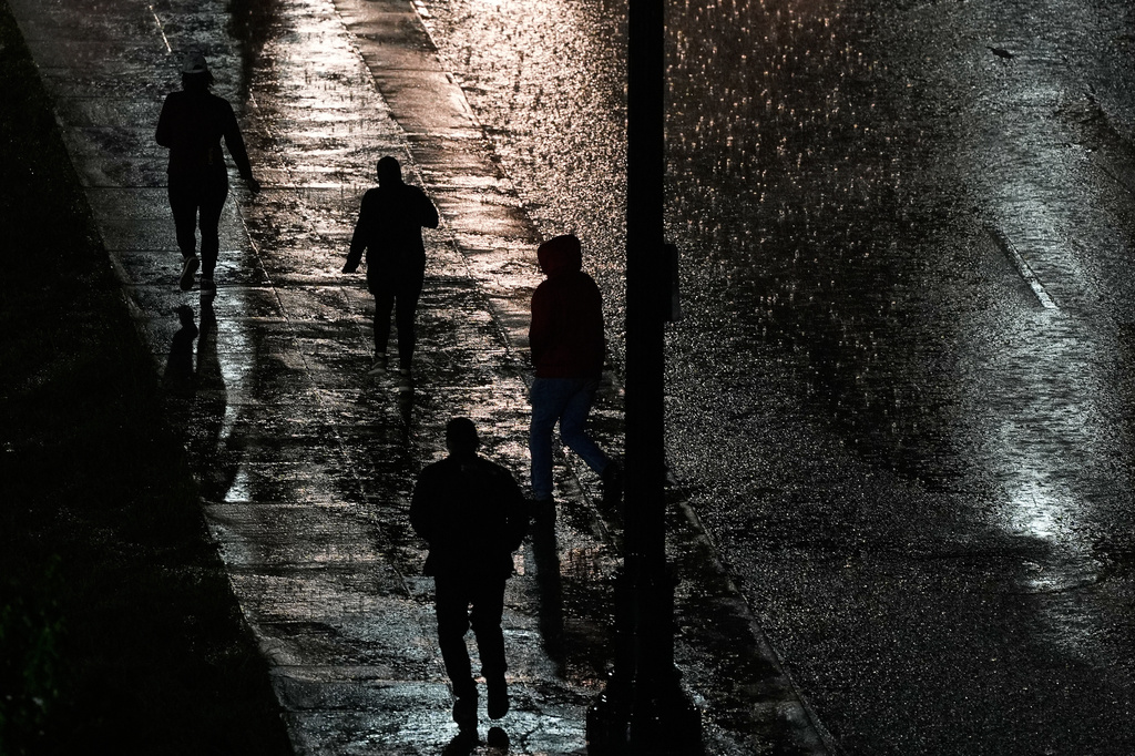 People walk in the rain as a thunderstorm moves through the area Thursday, April 23, 2026, in Kansas City, Mo. (AP Photo/Charlie Riedel)
