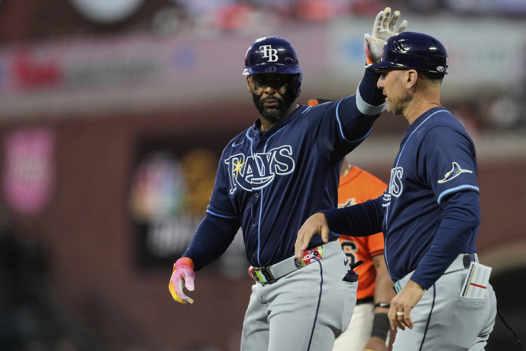 Tampa Bay Rays' Yandy Díaz, left, celebrates with first base coach Michael Johns, right, after hitting an RBI single during the third inning of a baseball game against the San Francisco Giants, Friday, Aug. 15, 2025, in San Francisco. (AP Photo/Godofredo A. Vásquez)