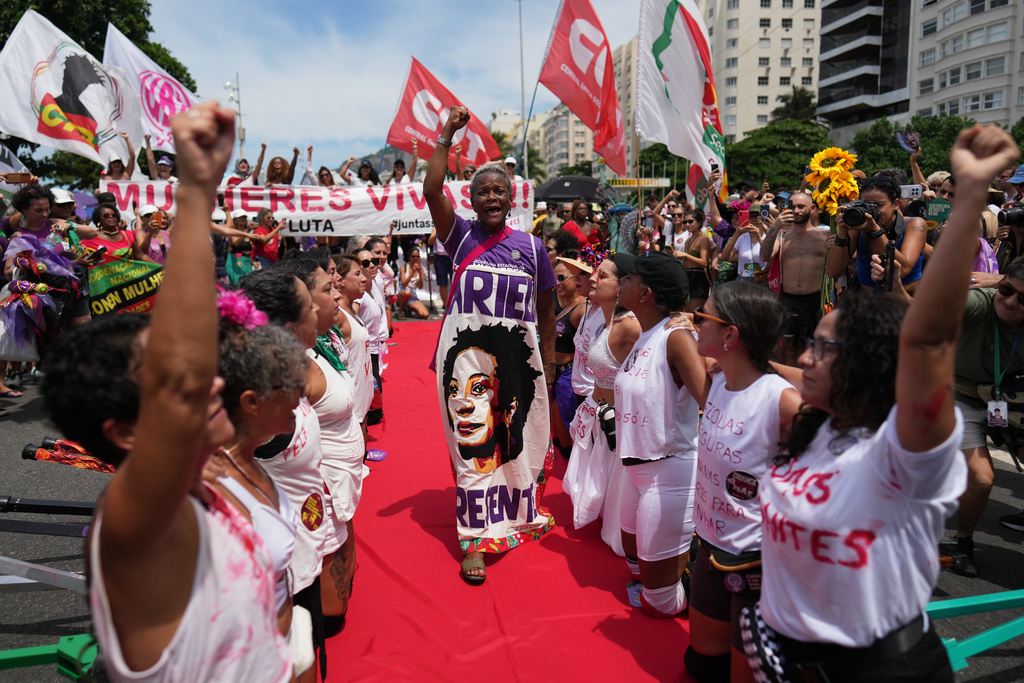 Women perform during a march marking International Women's Day on Copacabana beach, in Rio de Janeiro, Sunday, March 8, 2026. (AP Photo/Silvia Izquierdo)