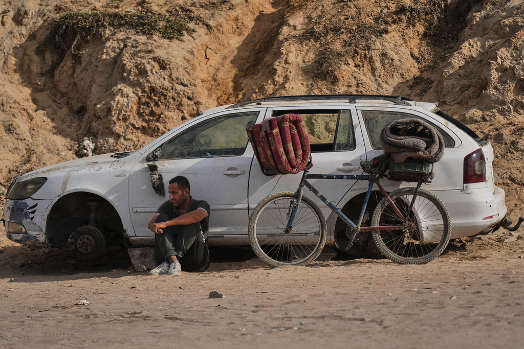 A displaced Palestinian man sits beside a bicycle as he waits on the coastal road near Wadi Gaza in the central Gaza Strip, Thursday, Oct. 9, 2025, during an attempt to return to Gaza City after the announcement that Israel and Hamas had agreed to the first phase of a peace plan to pause the fighting. (AP Photo/Abdel Kareem Hana)