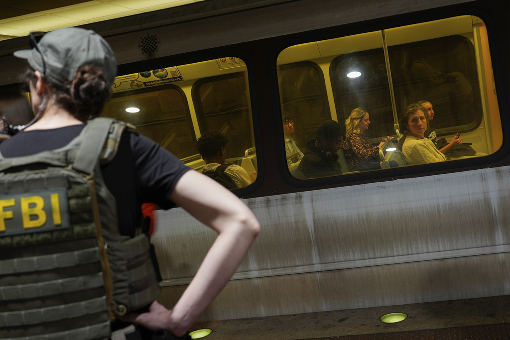 An FBI officer stands by as District of Columbia Metro Transit Police Department and Metropolitan Police Department officers detain three people at L'Enfant Plaza metro station, Thursday, Aug. 21, 2025, in Washington. (AP Photo/Julia Demaree Nikhinson)