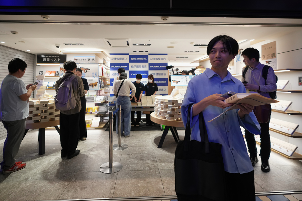 A man receives a copy of Haruki Murakami's new book titled "The Tale of KAHO" minutes after the clock struck midnight as others wait in line during a countdown event at a Kinokuniya bookstore in Tokyo, Friday, July 3, 2026. (AP Photo/Hiro Komae)