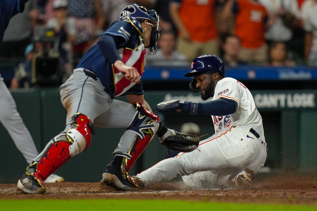 Houston Astros' Taylor Trammell, right, beats a tag by Tampa Bay Rays catcher Hunter Feduccia, left, to score on a sacrifice fly by designated hitter Yordan Alvarez during the seventh inning of a baseball game in Houston, Saturday, July 4, 2026. (AP Photo/Jon Shapley)