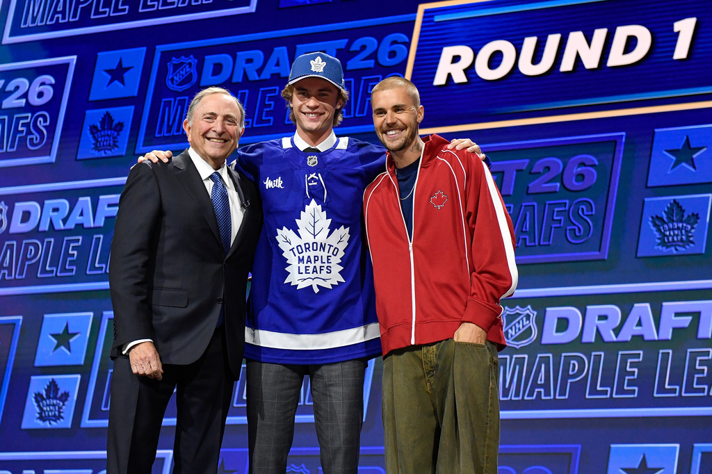 Gavin McKenna, center, stands with NHL Commissioner Gary Bettman, left, and singer Justin Bieber, right, after being drafted by the Toronto Maple Leafs during the NHL hockey draft Friday, June 26, 2026, in Buffalo, N.Y. (AP Photo/Adrian Kraus)