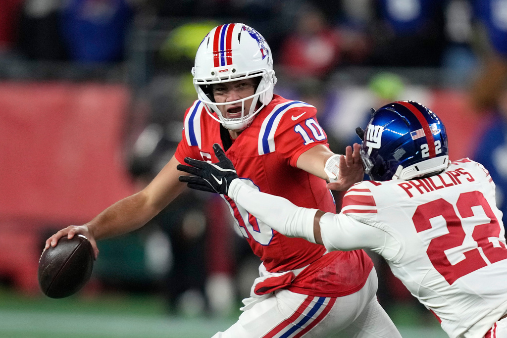 New England Patriots quarterback Drake Maye (10) stiff-arms New York Giants cornerback Dru Phillips (22) during the first half of an NFL football game Monday, Dec. 1, 2025, in Foxborough, Mass. (AP Photo/Charles Krupa)