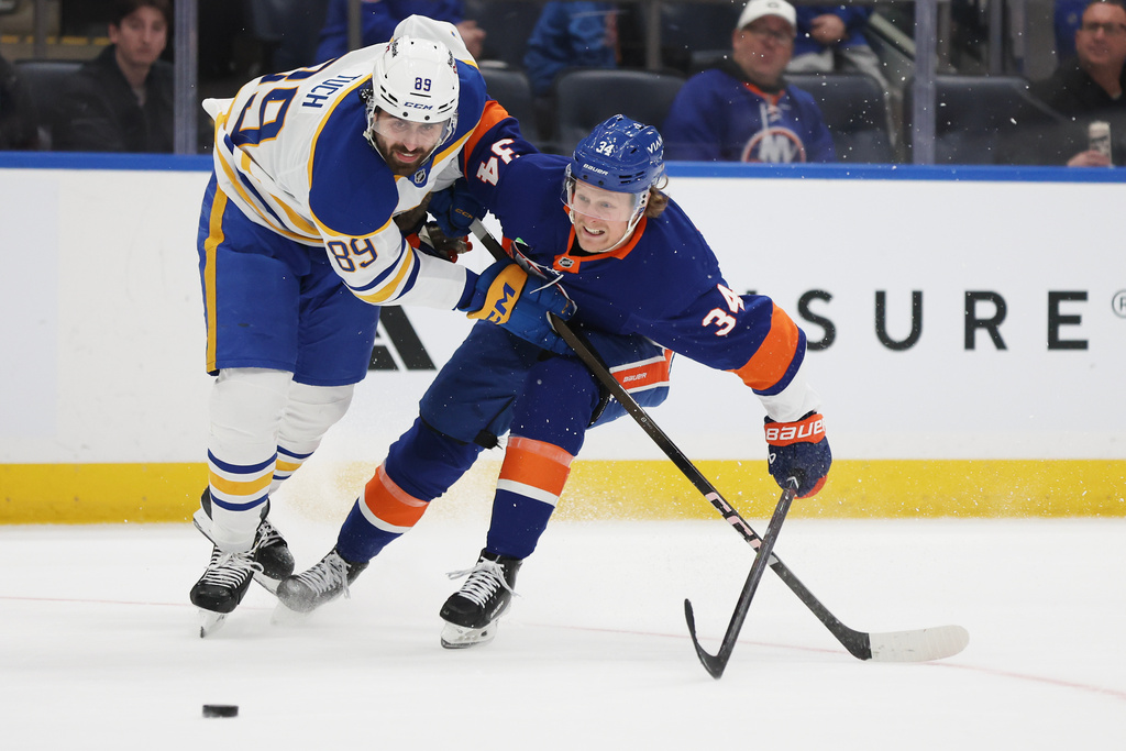 Buffalo Sabres right wing Alex Tuch (89) and New York Islanders defenseman Adam Boqvist (34) go after the puck during the third period of an NHL hockey game, Saturday, Jan. 24, 2026, in Elmont, N.Y. (AP Photo/Heather Khalifa)