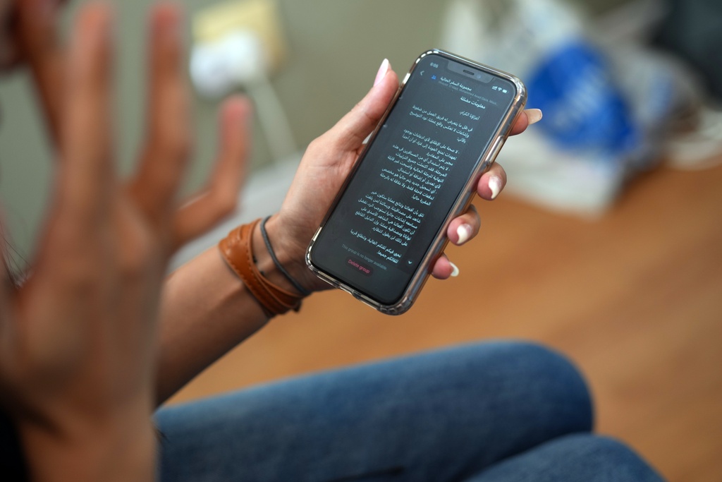 A Palestinian woman who traveled to South Africa via a charter flight organized by an Israeli group whose founder supported U.S. President Donald Trump's proposal to resettle Palestinians from Gaza, checks her phone in her temporary flat in Johannesburg, South Africa, Wednesday, Feb. 4, 2026. (AP Photo/Jerome Delay)