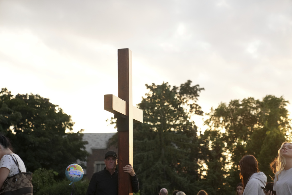 Dan beazley carries a cross at a memorial at Annunciation Catholic Church after Wednesday's school shooting, Thursday, Aug. 28, 2025, in Minneapolis. (AP Photo/Abbie Parr)