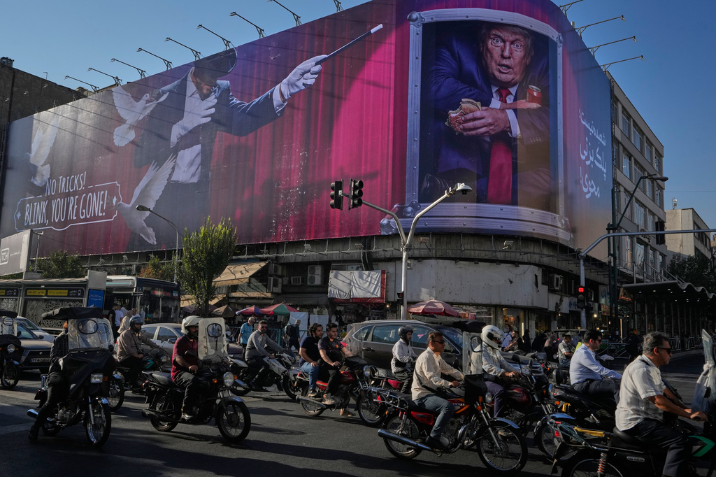 Motorcyclists ride past a billboard depicting U.S. President Donald Trump inside a catering container in downtown Tehran, Iran, Saturday, Aug. 29, 2026. (AP Photo/Vahid Salemi)