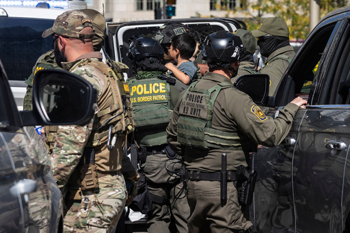A federal agent carries a child as agents detain someone near Pioneer Court off the Magnificent Mile, Sunday, Sept. 28, 2025, in Chicago. (Ashlee Rezin/Chicago Sun-Times via AP) A federal agent carries a child as agents detain someone near Pioneer Court off the Magnificent Mile, Sunday, Sept. 28, 2025, in Chicago. (Ashlee Rezin/Chicago Sun-Times via AP)