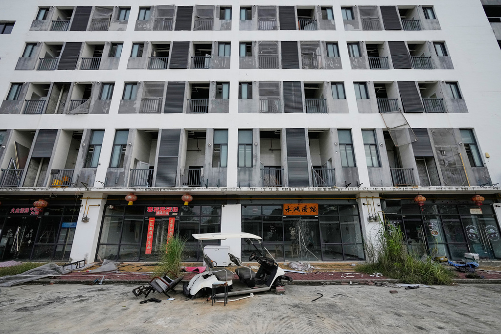 A damaged golf cart sits outside an abandoned residential building at the sprawling former Baofu scam compound that was raided by authorities last year in Bamban, Tarlac city, northern Philippines, Thursday, June 5, 2025. (AP Photo/Aaron Favila)