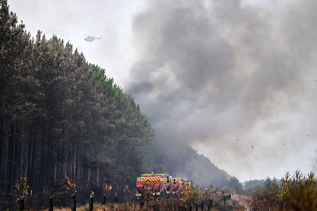 A helicopter provides support while firefighters tackle a blaze as wildfires rage near Le Las, outside Bordeaux, France, Monday, July 27, 2026. (AP Photo/Emma Da Silva)