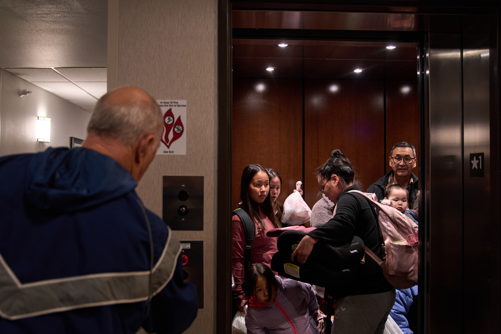 The Fox family, of Kipnuk, Alaska, get into a hotel elevator in Anchorage, Alaska as they move from temporary housing after being displaced from their village by Typhoon Halong earlier in the month, Wednesday, Oct. 29, 2025.. (AP Photo/Lindsey Wasson)