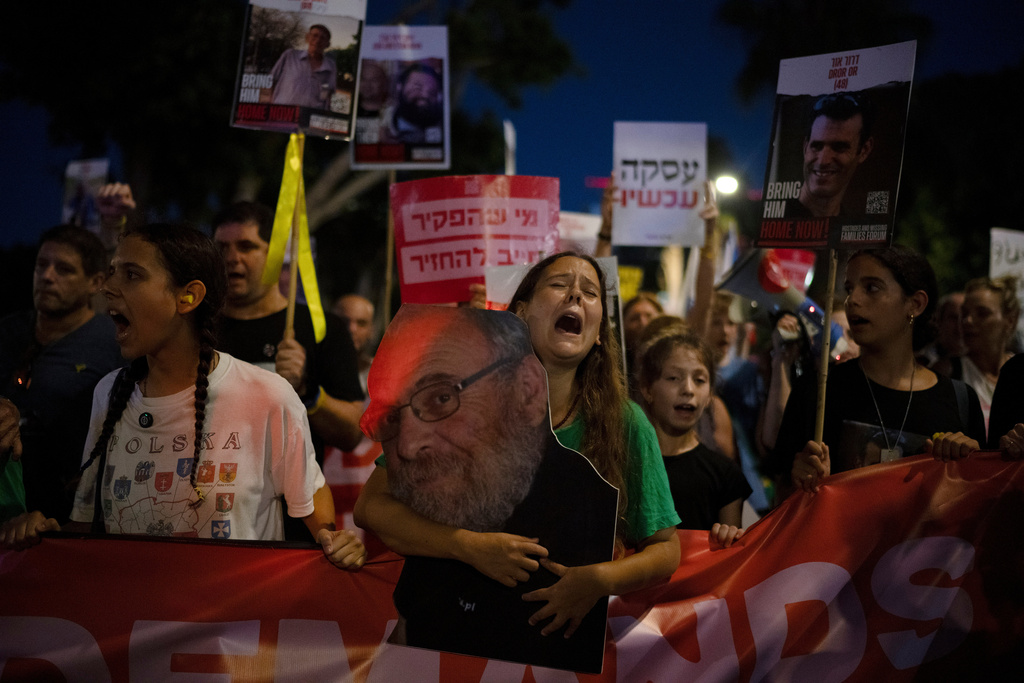 Eliya, holds a photo of her grandfather, Alex Dancyg, who according to the Israeli military died after being kidnapped by the Hamas militant group, during a rally calling for the release of hostages held in the Gaza Strip, in Tel Aviv, Israel, Tuesday, July 23, 2024. (AP Photo/Leo Correa)