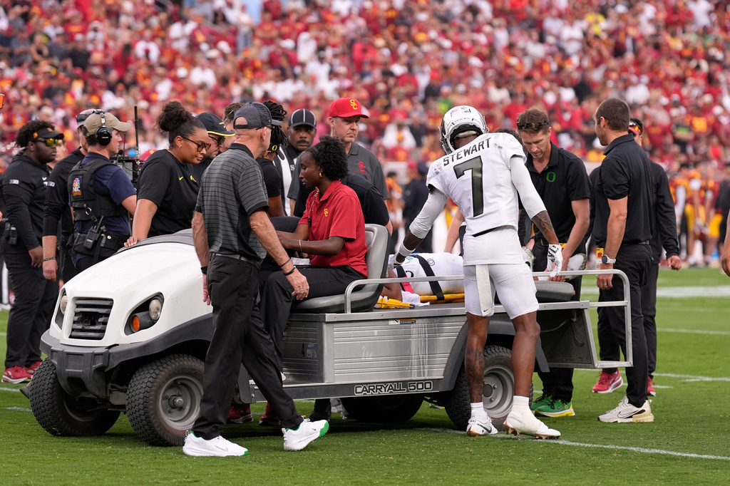 Oregon wide receiver Evan Stewart checks on as quarterback Dante Moore is carted off the field following a hard tackle by linebacker Desman Stephens II during the first half of an NCAA college football game, Saturday, Sept. 26, 2026, in Los Angeles. (AP Photo/Mark J. Terrill)